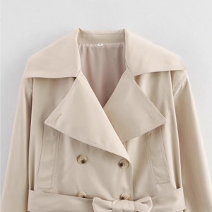 Detail of classic beige trench coat featuring amber double-breasted buttons and woven texture