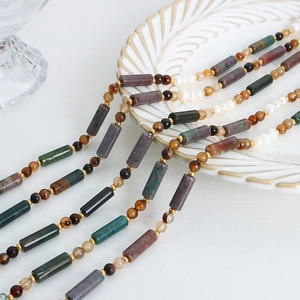 Handmade beaded necklace with natural stones, freshwater pearls and gold accents on a dish