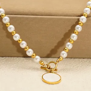 Elegant pearl necklace with golden OT buckle and shell pendant on leather stand