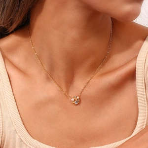 Detail view of a 18K gold plated flower necklace with pearls and crystals on a model