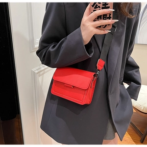 Detail of red leather crossbody bag with adjustable wide black textile shoulder strap