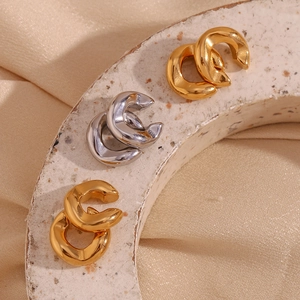 Macro shot of minimalist C-shape 18K gold and silver plated earrings on stone texture