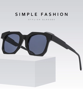Macro view of black geometric thick-frame sunglasses on a white minimalist pedestal
