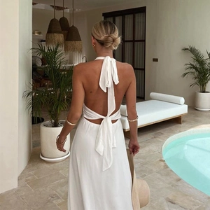 Detail view of white halter dress with lace-up back design and flowing vacation style