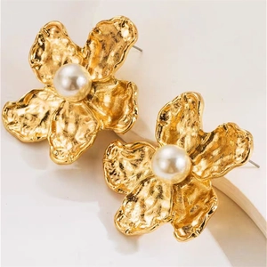 Detail of leaf-shaped gold stud earring with hammered texture and a white pearl accent