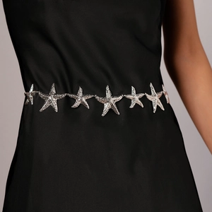Close-up of a silver metallic starfish waist chain worn over a elegant black dress