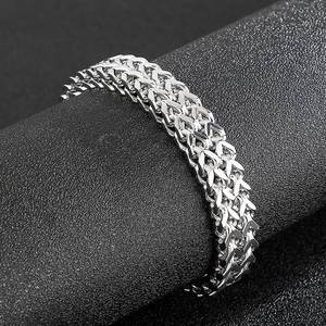 Macro shot of silver woven chain bracelet with vintage dragon head design and metal texture