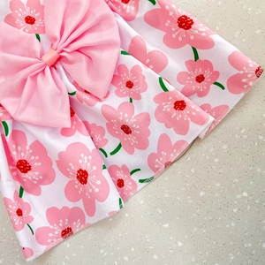 Detailed view of pink cherry blossom print fabric with large bow on a pet dress