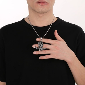 Detail of silver skull pendant with crossed revolvers on a male model with black t-shirt