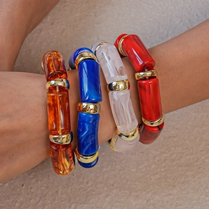 Macro shot of layered acrylic bamboo-style tube bracelets with golden metal spacers