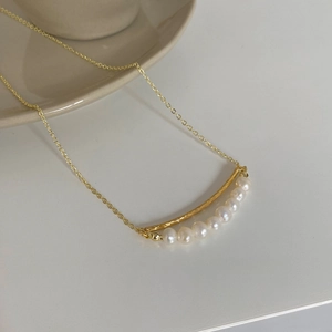Detailed view of baroque pearl curved pendant on a gold plated O-chain necklace