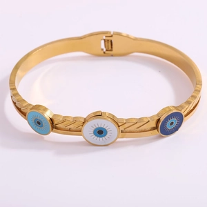 Detail of gold evil eye bangle with enamel charms and feathered texture surface