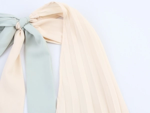 Detail of mint green and beige contrast stitching with pleated fabric textures