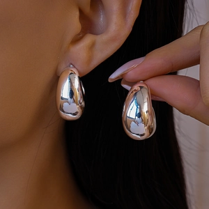 Close-up of polished silver teardrop stud earrings worn on a model's earlobe