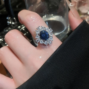 Détail de bague saphir bleu en zircon avec monture florale argentée et halo brillant