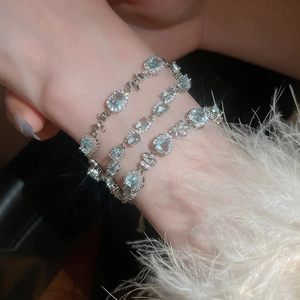 Detailed view of silver bracelets with aquamarine stones and bow-knot design on a wrist