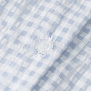 Detailed macro shot of light blue gingham seersucker fabric with white button detail