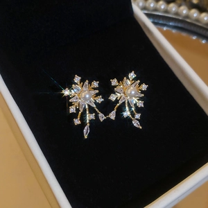 Detailed close-up of gold flower stud earrings with central pearl and sparkling zircon stones