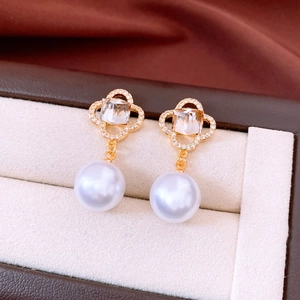 Macro detail of vintage pearl clover earring with zircon inlay and gold finish texture