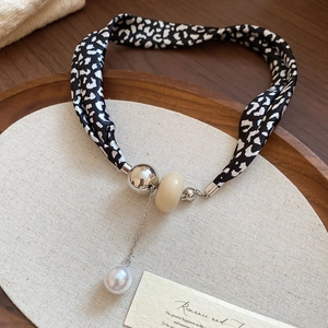 Détail du collier ras de cou en soie léopard avec perles métalliques et un pendentif perle