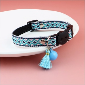 Detail of woven plaid cat collar with blue bell and tassel on ceramic plate