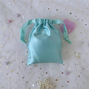 Detail of mint green satin drawstring pouch for jewelry storage on star mesh background