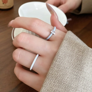 Detail of silver wavy rings and light blue gemstone ring worn by a model on hand