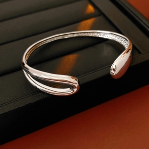 Macro view of silver teardrop hollow bangle showing sleek metal texture and modern design