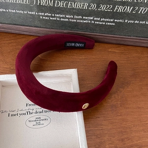 Detailed macro view of wine red velvet padded headband with elegant golden metal logo