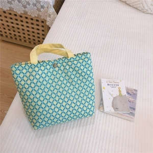 Detail of floral quilted bento bag with yellow handles and metal snap closure