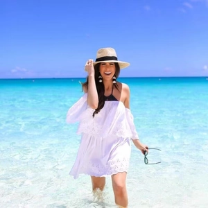 Bohemian white off-shoulder lace dress with ruffles and sun hat on a sunny beach