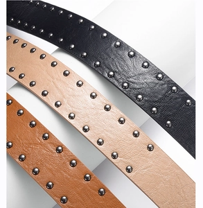 Detailed view of three punk style leather belts with double row metal silver rivets
