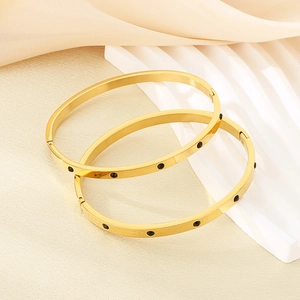 Close-up of dual gold bangle set with black crystal inlay on premium silk fabric
