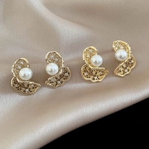 Detailed close-up of hollow butterfly pearl earrings with zircon on silk fabric