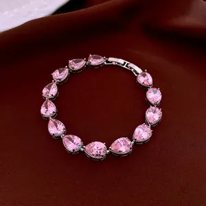 Elegant silver bracelet with pear-cut pink gemstones on a deep red velvet background