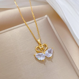 Macro detail of golden double swan pendant with sparkling teardrop crystals on silk