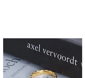 Close-up of a minimalist gold wave-patterned ring resting on a book background