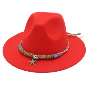 Dettaglio di cappello fedora rosso con fascia etnica intrecciata e ciondolo a stella