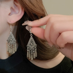 Detailed shot of vintage silver flower earrings with hanging metallic tassels on a model