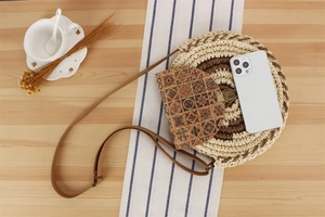 Detailed top view of round woven crossbody bag with geometric ethnic print on wooden table