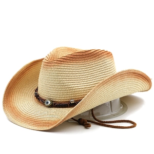 Detail of woven straw cowboy hat featuring a gradient finish and Evil Eye bead ornament