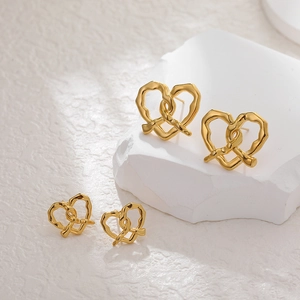 18K gold plated stainless steel woven heart stud earrings on white stone display