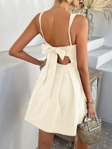 Rear view of an elegant cream white sundress featuring a large back bow and cutout detail