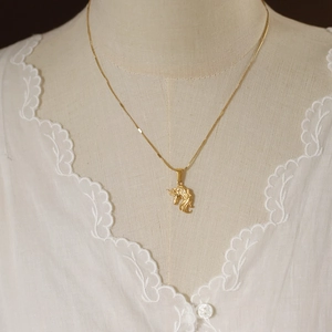Macro shot of gold-plated unicorn pendant on a delicate chain with vintage details