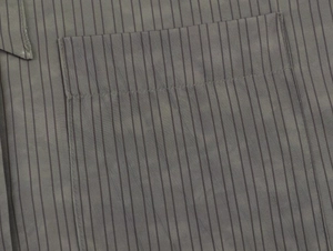 Detail of the chest pocket and sewing craftsmanship on the striped grey-green shirt