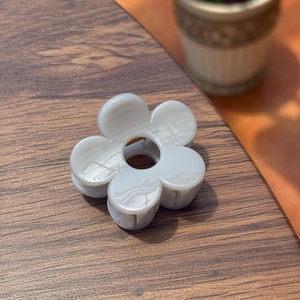 Gros plan d'une pince à cheveux fleur gris clair de 5 cm sur une surface en bois sombre