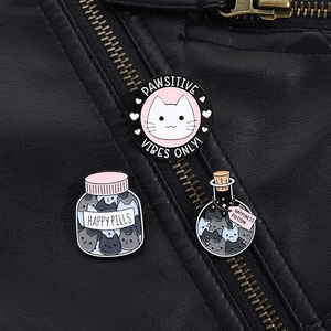 Detail of cartoon cat enamel pins with Pawsitive Vibes Only text on a black leather jacket