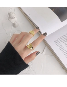 Detail of gold coin relief ring and irregular wavy open ring on hand with aesthetic props