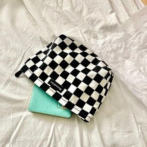 Detail of checkered makeup bag with zipper closure showing spacious interior storage