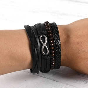 Men's multilayer leather bracelet set with silver infinity symbol on white wood table